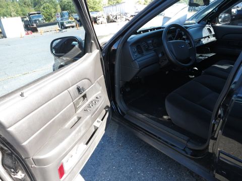 2001 Ford Crown Victoria - The interior of a black vehicle is visible, including the dashboard, steering wheel, and seats.