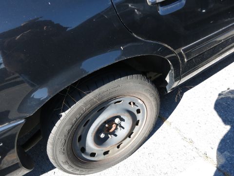 2001 Ford Crown Victoria - Close-up of a black car's rear wheel well and tire, with visible tire text.
