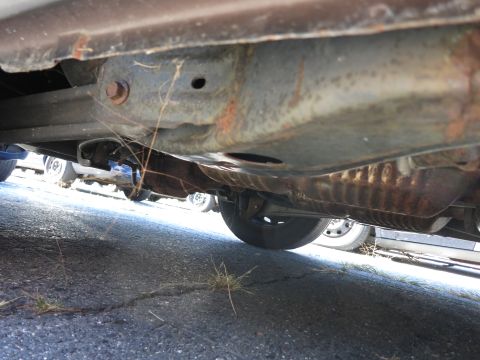 2001 Ford Crown Victoria - The underside of a vehicle is shown, with visible rust and multiple other vehicles in the background.