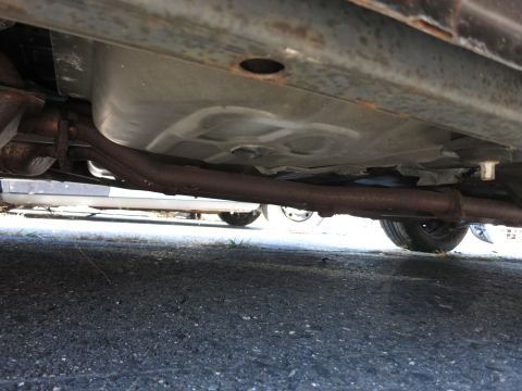 2001 Ford Crown Victoria - The underside of a vehicle is visible, the exhaust pipe and fuel tank, with a portion of a tire in the foreground.