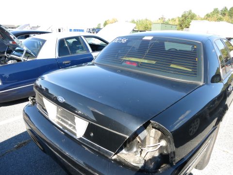 2001 Ford Crown Victoria - A black Ford Crown Victoria is seen from the rear, with a damaged taillight and blinds on the window.