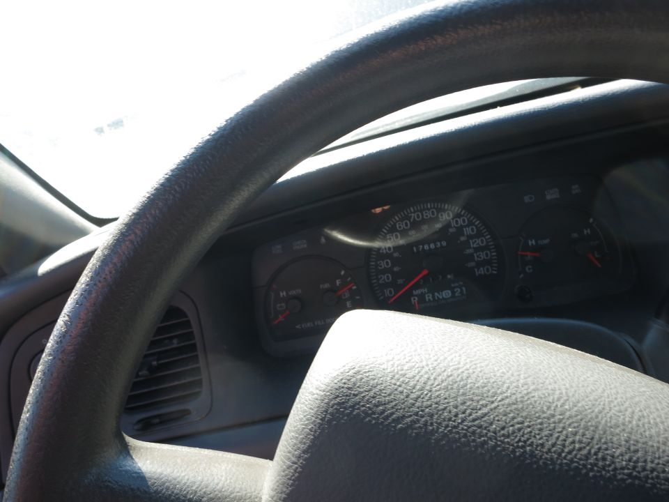 2001 Ford Crown Victoria interior showing steering wheel and dashboard gauges with odometer reading 176836