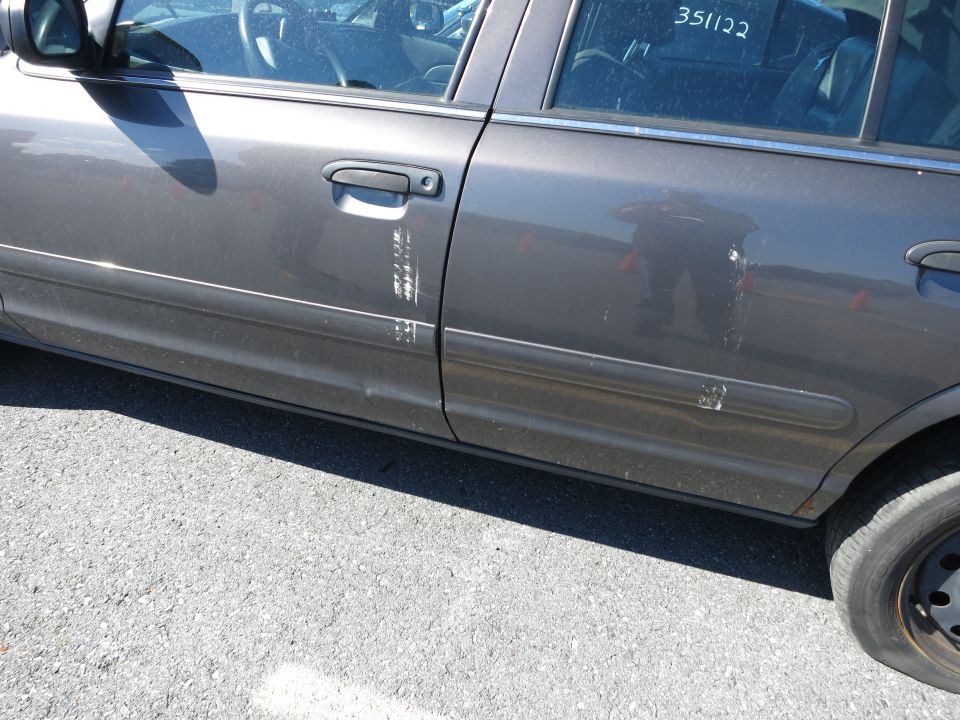 Side view of a gray 2001 Ford Crown Victoria with scuff marks on the driver's side doors