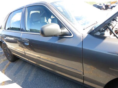 2001 Ford Crown Victoria - The side profile of a dark gray sedan is visible, with the hood propped open to reveal the engine bay.