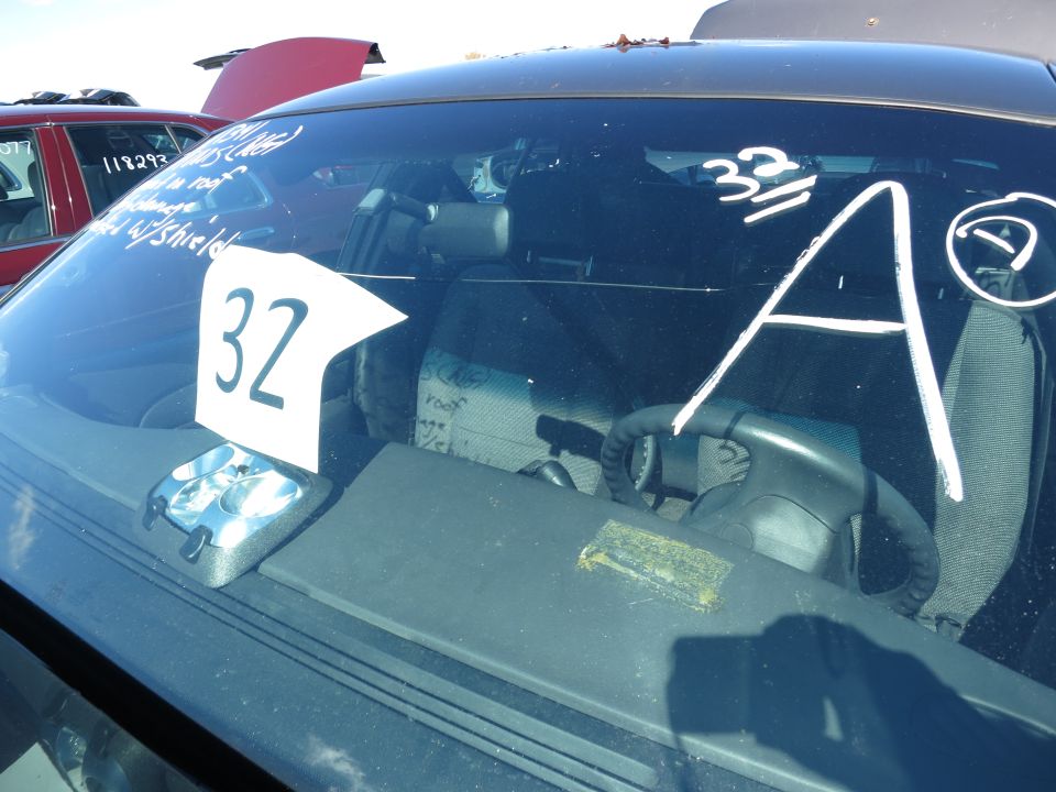 Car interior with a white sign showing '32' on the dashboard and white markings '32' and 'A' on the windshield