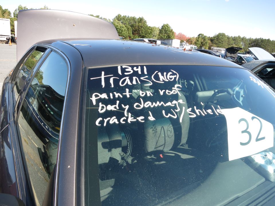 Dark sedan side view, hood and trunk open, windshield has handwritten notes