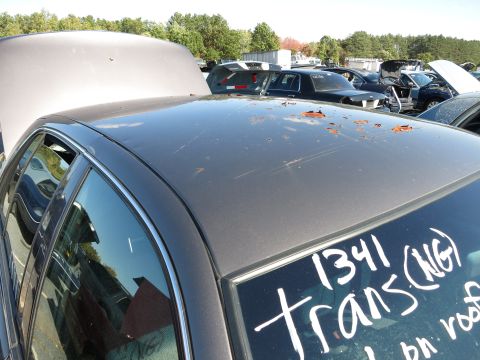 2001 Ford Crown Victoria - Junkyard scene with a car roof in focus, showing damage and handwritten markings.