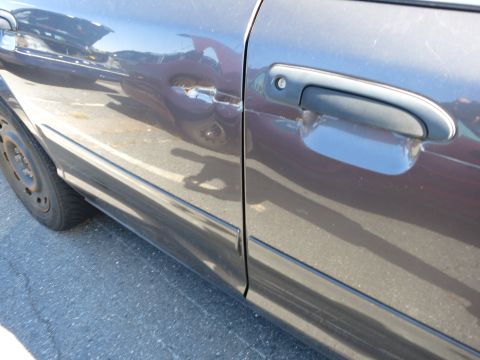 2001 Ford Crown Victoria - The side of a car shows damage to the door panel and a reflection of another vehicle.