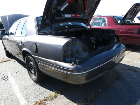 2001 Ford Crown Victoria - A gray 2001 Ford Crown Victoria is parked in a lot with its trunk open, revealing missing taillights.