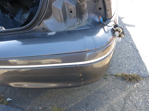 2001 Ford Crown Victoria - Close-up of a car's rear bumper and exposed trunk area, showing wiring for the taillight assembly.