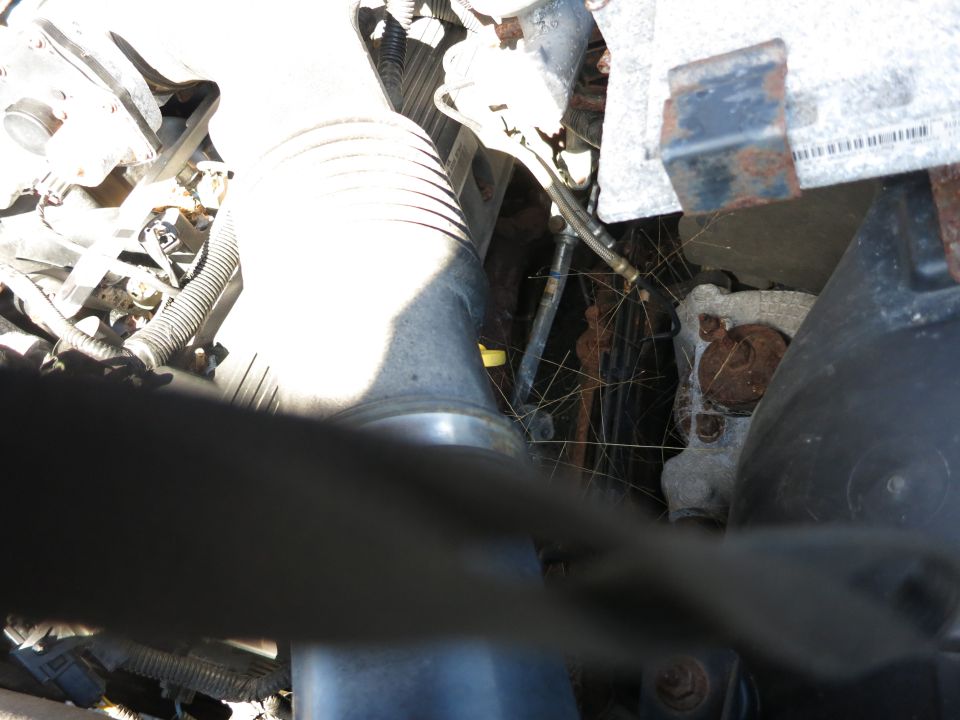 Engine compartment with cobwebs, rust, and a large air intake tube