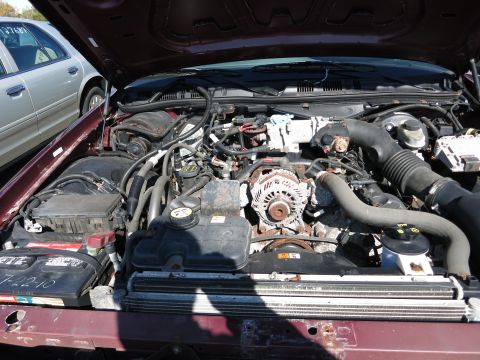 2001 Ford Crown Victoria - Engine bay of a maroon 2001 Ford Crown Victoria. Another vehicle is parked to the left.