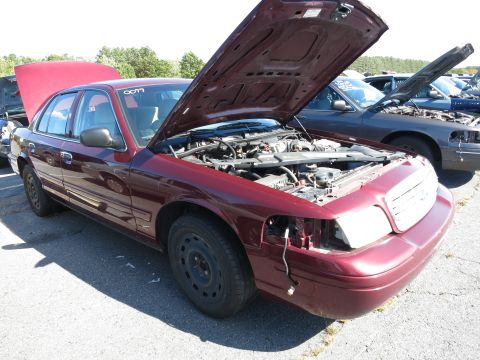 2001 Ford Crown Victoria - A maroon sedan sits in a lot with its hood open, revealing the engine compartment. Another vehicle is visible behind it.