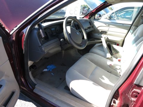2001 Ford Crown Victoria - The interior of a maroon 2001 Ford Crown Victoria is visible, with the driver's side door open. Another vehicle is parked nearby.