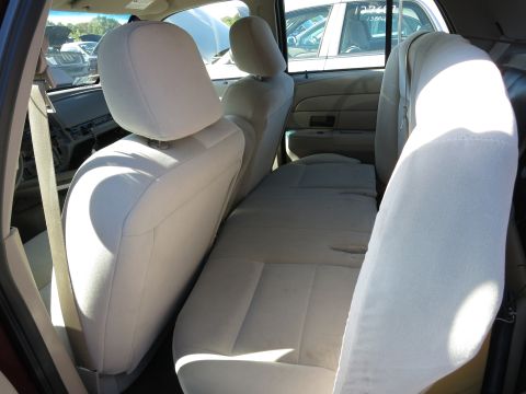 2001 Ford Crown Victoria - Interior view of a 2001 Ford Crown Victoria, showing the seats and dashboard area. Other cars are visible outside.