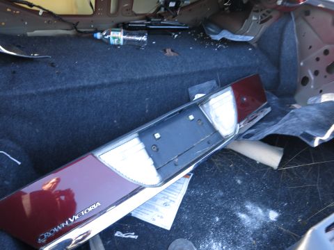 2001 Ford Crown Victoria - The interior of a car trunk shows a disassembled taillight assembly and a discarded water bottle.