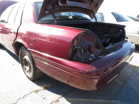 2001 Ford Crown Victoria - Rear view of a maroon sedan with its trunk open, showing damage to the taillight area and bumper.