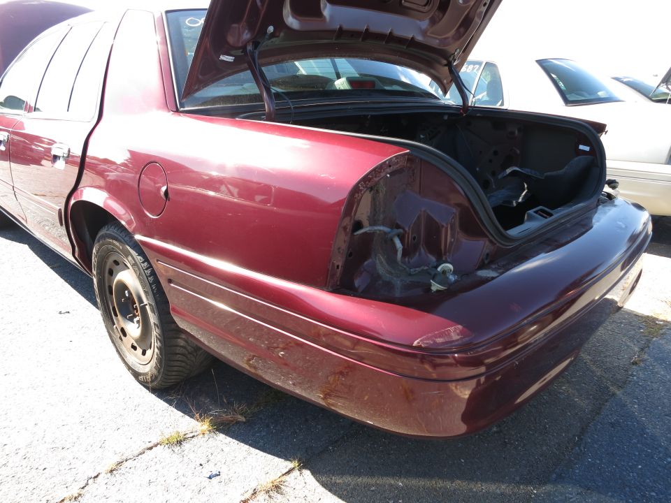 Maroon sedan, rear view, trunk open, missing taillight assembly, dented bumper