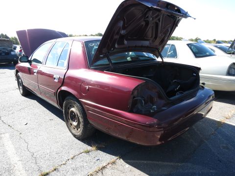 2001 Ford Crown Victoria - A maroon 2001 Ford Crown Victoria is seen with its trunk and hood open, parked outdoors with other vehicles visible.