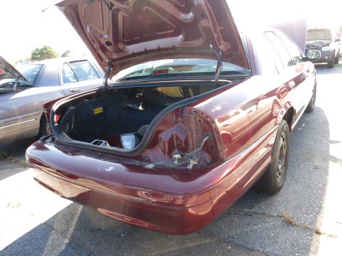 2001 Ford Crown Victoria - Rear view of a maroon 2001 Ford Crown Victoria showing its open trunk and missing taillight assembly.