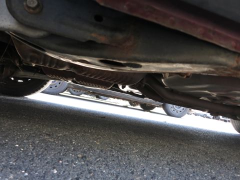 2001 Ford Crown Victoria - Underside view of a car's exhaust system and frame, with other vehicles visible in the background.