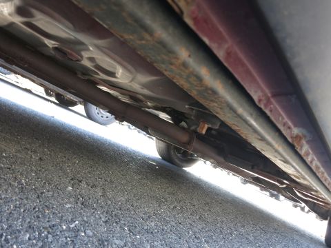 2001 Ford Crown Victoria - The undercarriage of a vehicle is visible, with the exhaust pipe and frame showing signs of wear and rust.