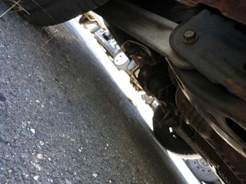 2001 Ford Crown Victoria - A low-angle view of a vehicle's undercarriage reveals suspension parts and a tire.