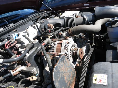 2001 Ford Crown Victoria - Close-up of a car's engine bay, focusing on the alternator and surrounding components.