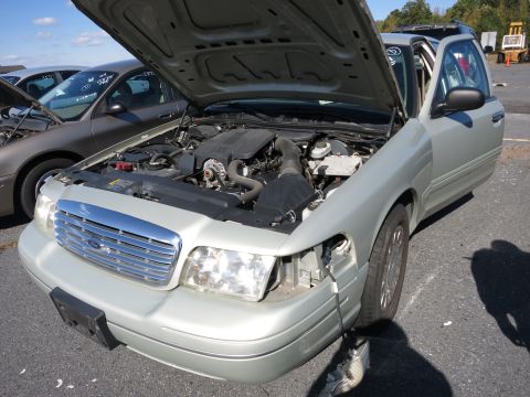 2001 Ford Crown Victoria - This 2001 Ford Crown Victoria is shown with its hood open, revealing the engine compartment and a prominent chrome grille.