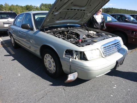 2001 Ford Crown Victoria - A silver sedan, possibly a 2001 Ford Crown Victoria, is parked with its hood open, revealing the engine compartment.