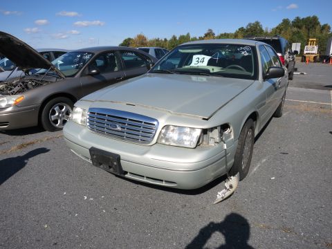 2001 Ford Crown Victoria - A silver 2001 Ford Crown Victoria is parked in an outdoor lot with visible front-end damage.