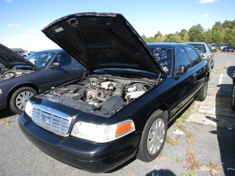 2001 Ford Crown Victoria - A black 2001 Ford Crown Victoria is parked with its hood open, revealing the engine compartment.