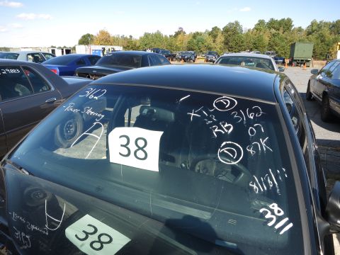 2001 Ford Crown Victoria - Windshield markings and signs on a black sedan in an outdoor lot with other vehicles.