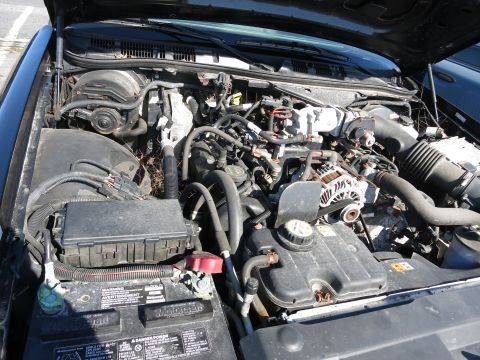 2001 Ford Crown Victoria - The engine bay of a 2001 Ford Crown Victoria is visible with the hood open, revealing the V8 engine components.
