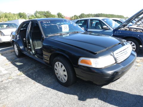 2001 Ford Crown Victoria - A black 2001 Ford Crown Victoria is parked outside with its driver's door ajar.