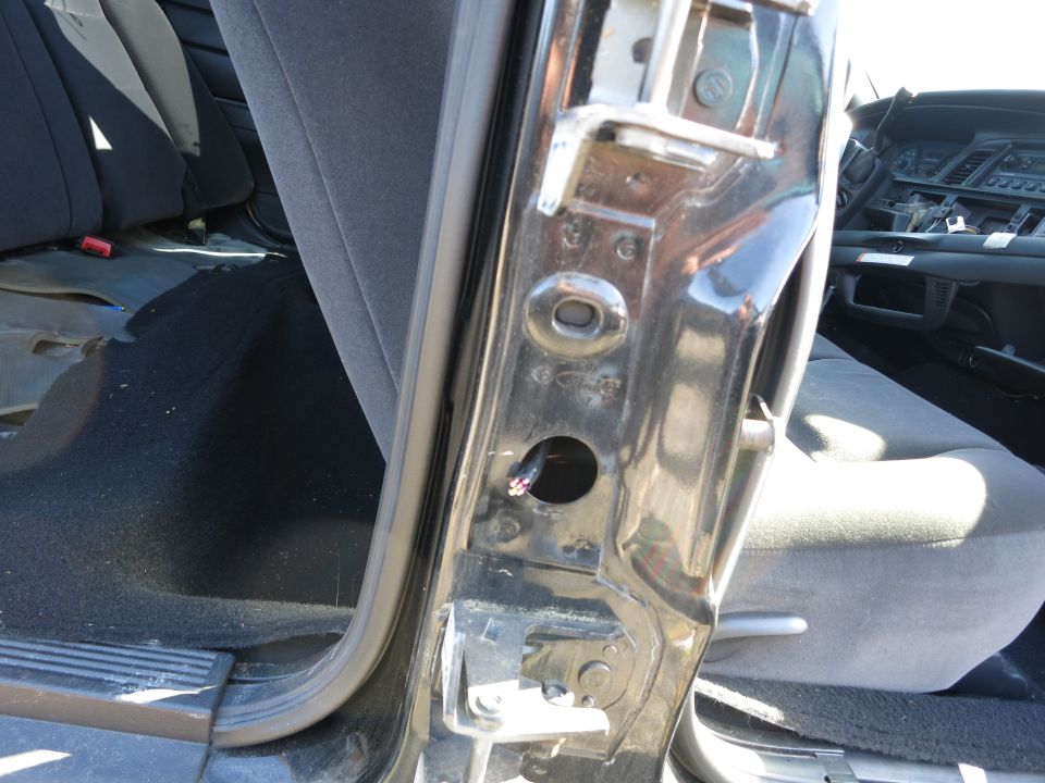 Car interior door jamb with exposed wires and grey seats visible