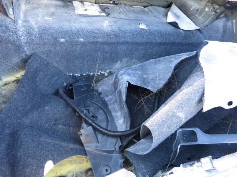 2001 Ford Crown Victoria - The interior of a car shows damage and disarray, with carpet pulled back and wiring exposed.