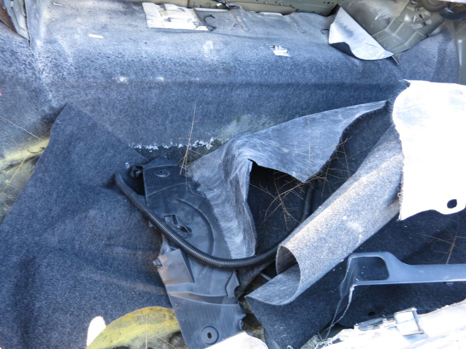 Car interior with torn carpet and exposed wiring
