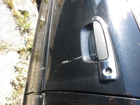 2001 Ford Crown Victoria - Scratched black car door handle and side panel detail.