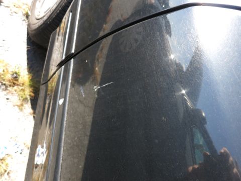 2001 Ford Crown Victoria - Close-up of a black car door showing scratches and a reflective surface.