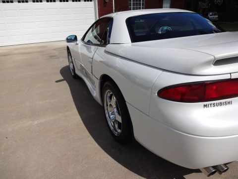 1995 Mitsubishi 3000GT - Rear view of a white 1995 Mitsubishi 3000GT parked in front of a garage.