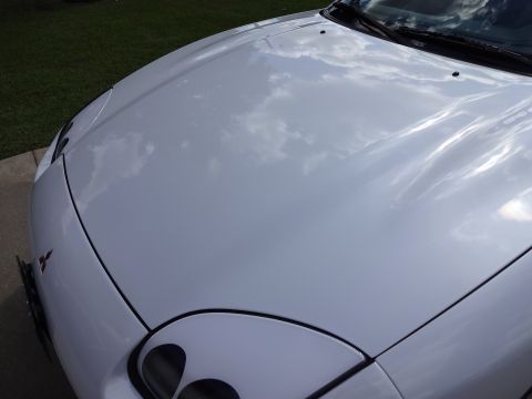1995 Mitsubishi 3000GT - The front fender and hood of a white 1995 Mitsubishi 3000GT show reflections of the sky.