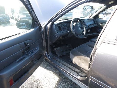 2001 Ford Crown Victoria - The interior of a sedan is shown with the driver's side door open, revealing the dashboard and seats.