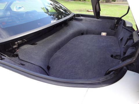 1995 Mitsubishi 3000GT - The trunk compartment of a car, lined with grey carpet, shows the storage area and its internal mechanisms.