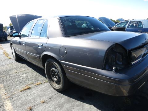 2001 Ford Crown Victoria - This 2001 Ford Crown Victoria is seen in a junkyard with its hood and trunk open, showing damage to the rear.