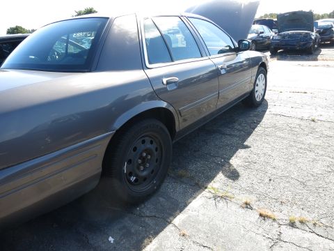 2001 Ford Crown Victoria - Side view of a 2001 Ford Crown Victoria, hood open, in a junkyard or impound lot.