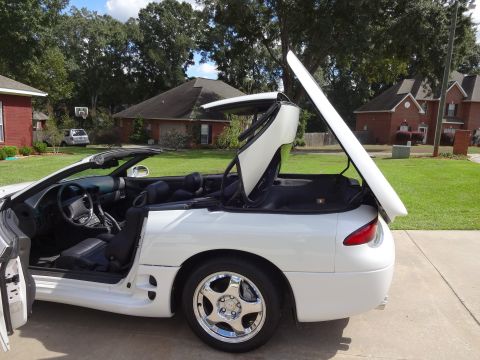 1995 Mitsubishi 3000GT - A white 1995 Mitsubishi 3000GT convertible is parked in a driveway with its top partially open.