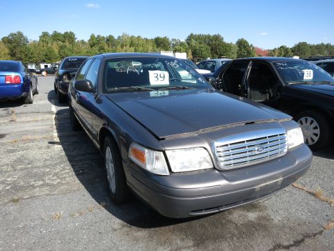 2001 Ford Crown Victoria - A dark gray 2001 Ford Crown Victoria is parked in an outdoor lot, with other vehicles visible in the background.