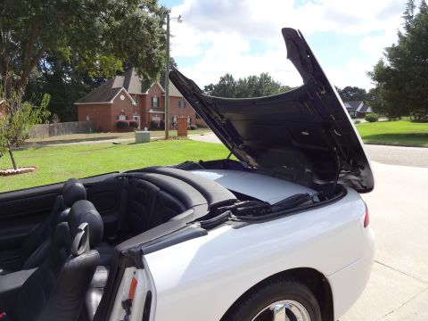 1995 Mitsubishi 3000GT - The hood of a white convertible is open, revealing the interior and the underside of the hood.