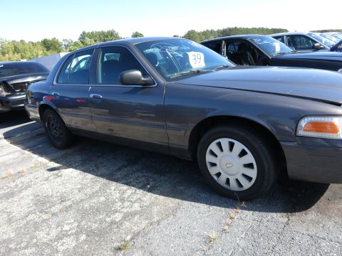 2001 Ford Crown Victoria - Side view of a dark gray 2001 Ford Crown Victoria, parked outdoors with other vehicles.